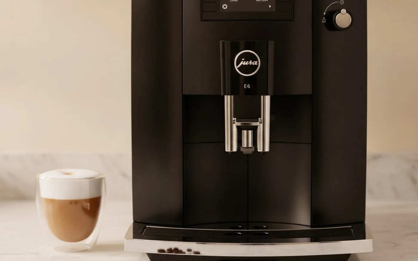 Jura E6 in chrome, positioned on a counter with espresso cup