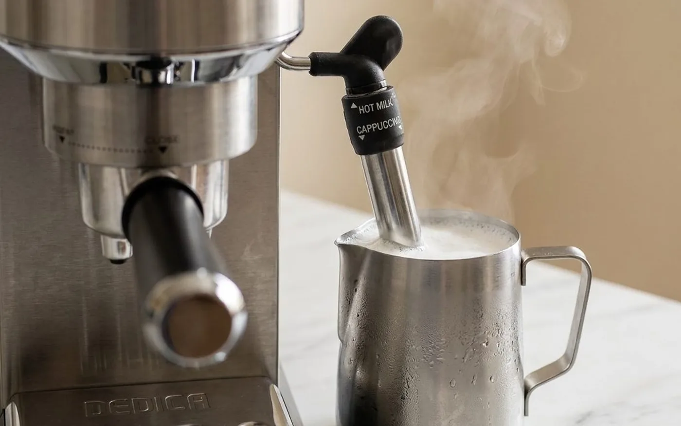 De’Longhi Dedica Pannarello steam wand frothing milk in a stainless steel jug