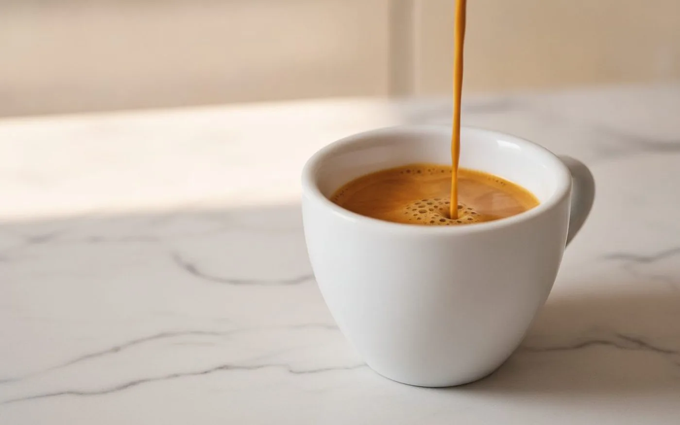 Ideal espresso extraction - narrow amber mouse-tail stream into white demitasse cup