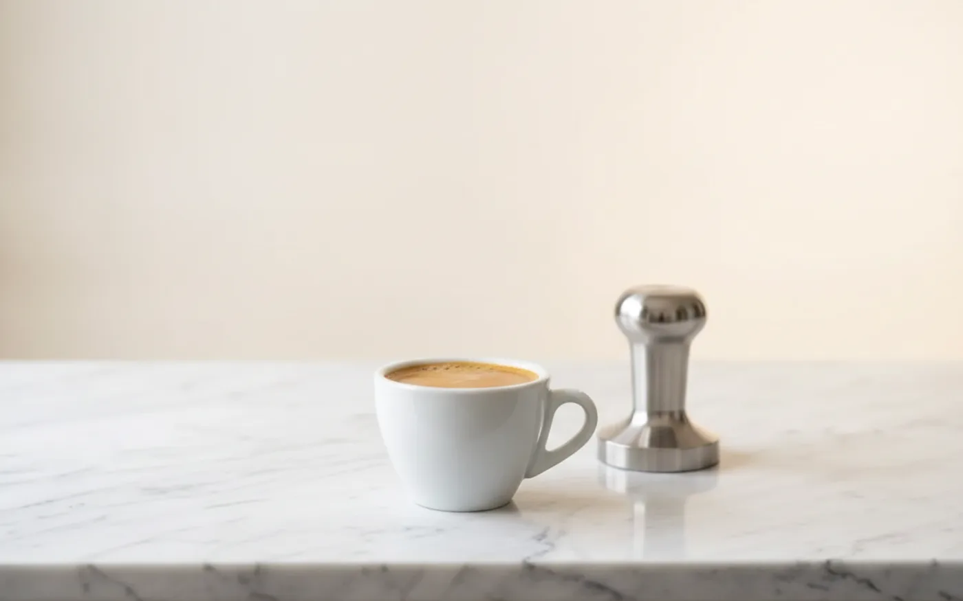 Espresso shot with golden crema on white marble surface