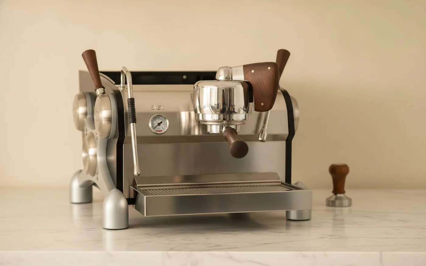 Slayer single-group espresso machine in black with wooden actuators and X-frame side panel on white marble