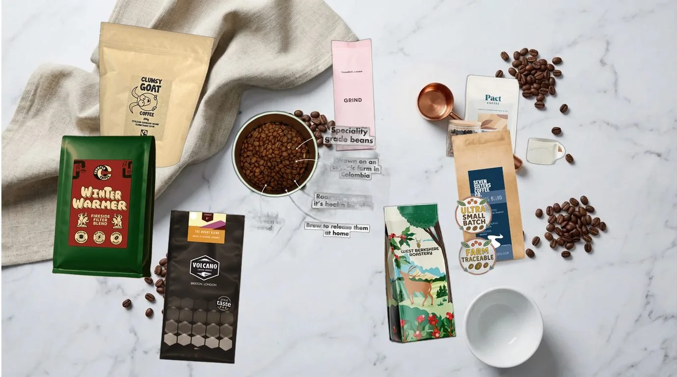 Best low acid coffee UK 2026 — selection of speciality coffee bean bags arranged on white marble with linen napkin and copper scoop